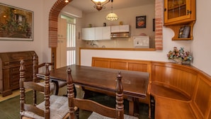 A dining area with a wooden table and chairs, a kitchen in the background, and a brick archway. - Lovely little house a few meters from the beach of the romantic Manerba (Manerba)