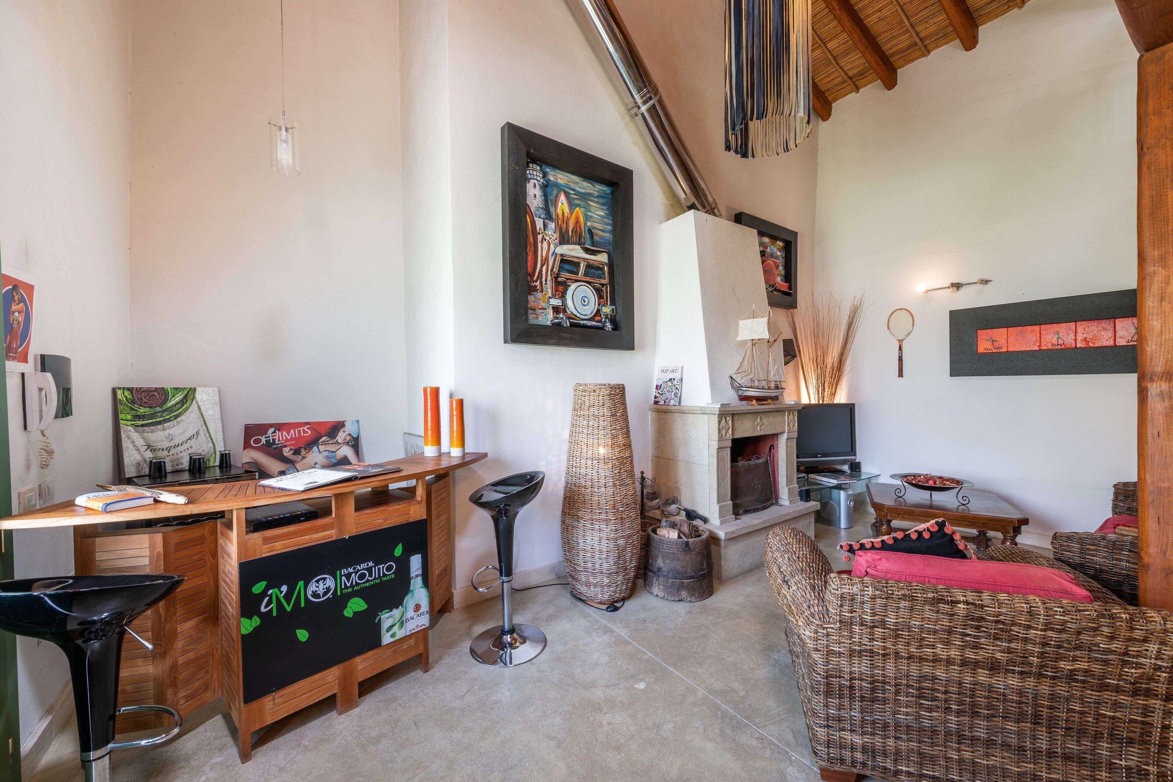 A cozy living room with a fireplace, a dining area with a wooden table, and a seating area with a wicker sofa.