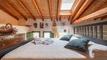 Een slaapkamer met een hoog houten plafond, een bed met kussens, een dressoir en een surfboard aan de muur.