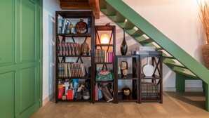 Una escalera con barandillas verdes, techo de madera y una estantería llena de libros y adornos.