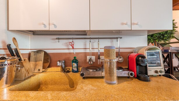 Cocina con encimera de granito, cafetera, tostadora y diversos utensilios.