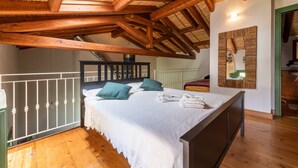 Un dormitorio con techo de madera, una cama con almohadas y un espejo montado en la pared.