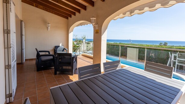 A covered outdoor area with a pool, seating, and a view of the sea. - Vacation Home "Villa Primavera" with Sea View and Pool (son bou, Alaior)