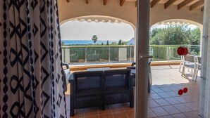 An open patio with a view of the sea, a covered seating area, and a glass balustrade. - Vacation Home "Villa Primavera" with Sea View and Pool (son bou, Alaior)
