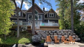 A lakeside cabin with a dock, wooden deck, and Adirondack chairs. - Beautiful open-concept cottage on Moon River! 10 Minute walk to Bala! (Bala)