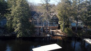 A lakeside cabin with a dock, surrounded by dense trees. - Beautiful open-concept cottage on Moon River! 10 Minute walk to Bala! (Bala)