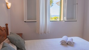 A bedroom with a bed, pillows, a window with curtains, and a wall-mounted light. - Vacation Home "Villa Llebeig" Near the Beach with Sea View and Pool (San Jaime Mediterráneo)