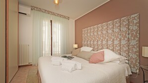 A neatly made bed with towels, a bedside lamp, and a floral-patterned headboard.
