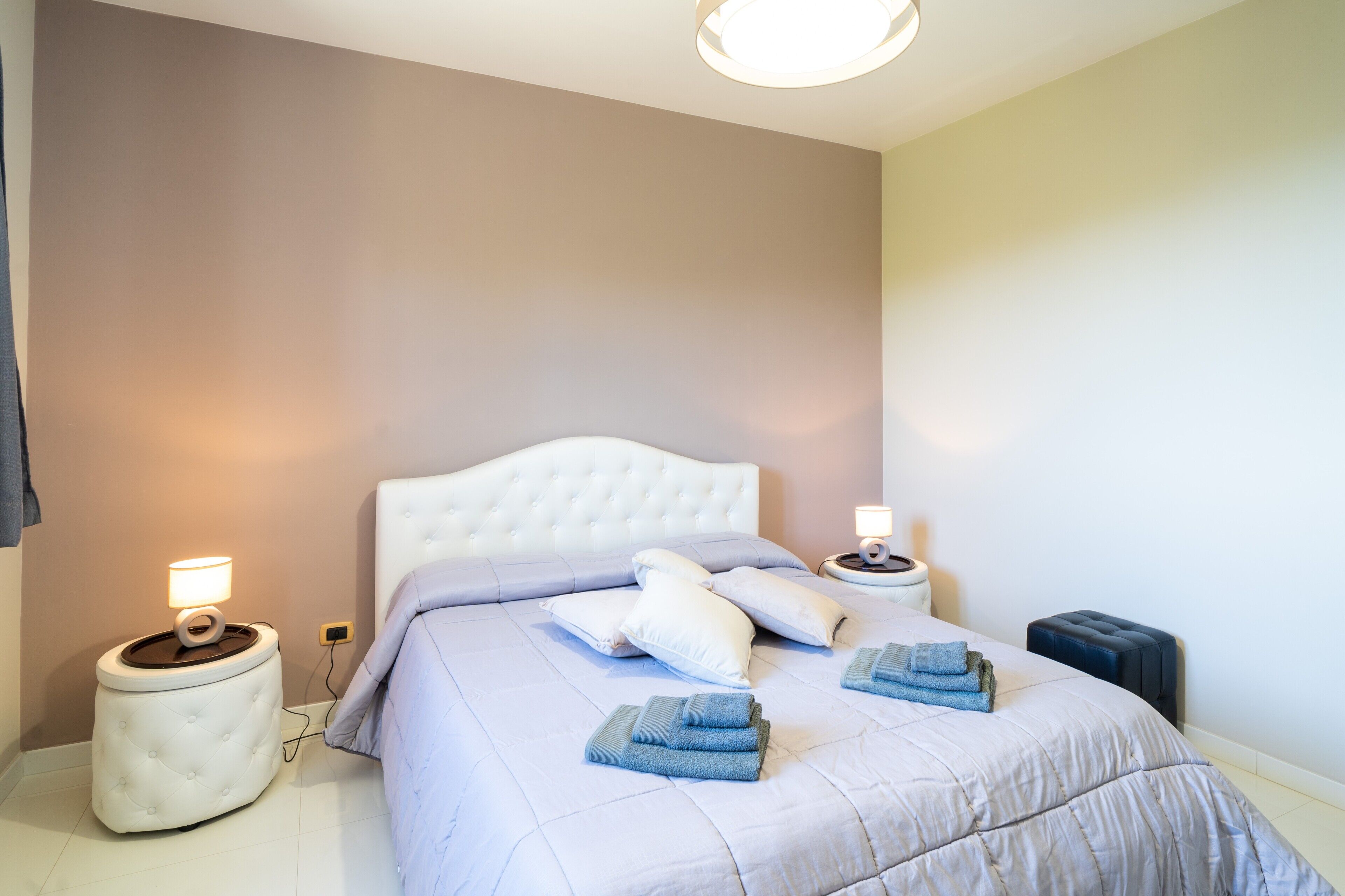 Un dormitorio con cama, dos mesitas de noche y una lámpara de pared.