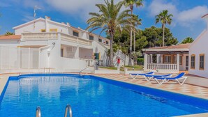 A swimming pool with a clear blue water, surrounded by white buildings with balconies and palm trees. - Beautiful apartment with porch, pool, garden and Wi-Fi (Son Xoriguer)