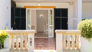 A building entrance with a tiled floor, a white door, and a small table with chairs inside. - Beautiful apartment with porch, pool, garden and Wi-Fi (Son Xoriguer)