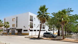 Un bâtiment blanc avec une enseigne indiquant « CAMPO & HOGAR », une voiture garée et des palmiers.