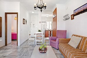 Una sala de estar con sofá, sillón, mesa de comedor y candelabro.
