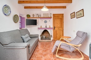 A living room with a sofa, a rocking chair, a fireplace, and a television.