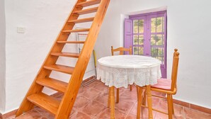 A wooden staircase, a round table with a lace tablecloth, and a purple door with a window. - Holiday Home 'Casa Rural El Tesillo' with Mountain View and Wi-Fi (Canillas de Aceituno)