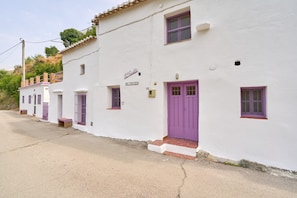 A row of white buildings with purple doors and windows, a sign reading 'El Castillo,' and a small staircase leading to the entrance.