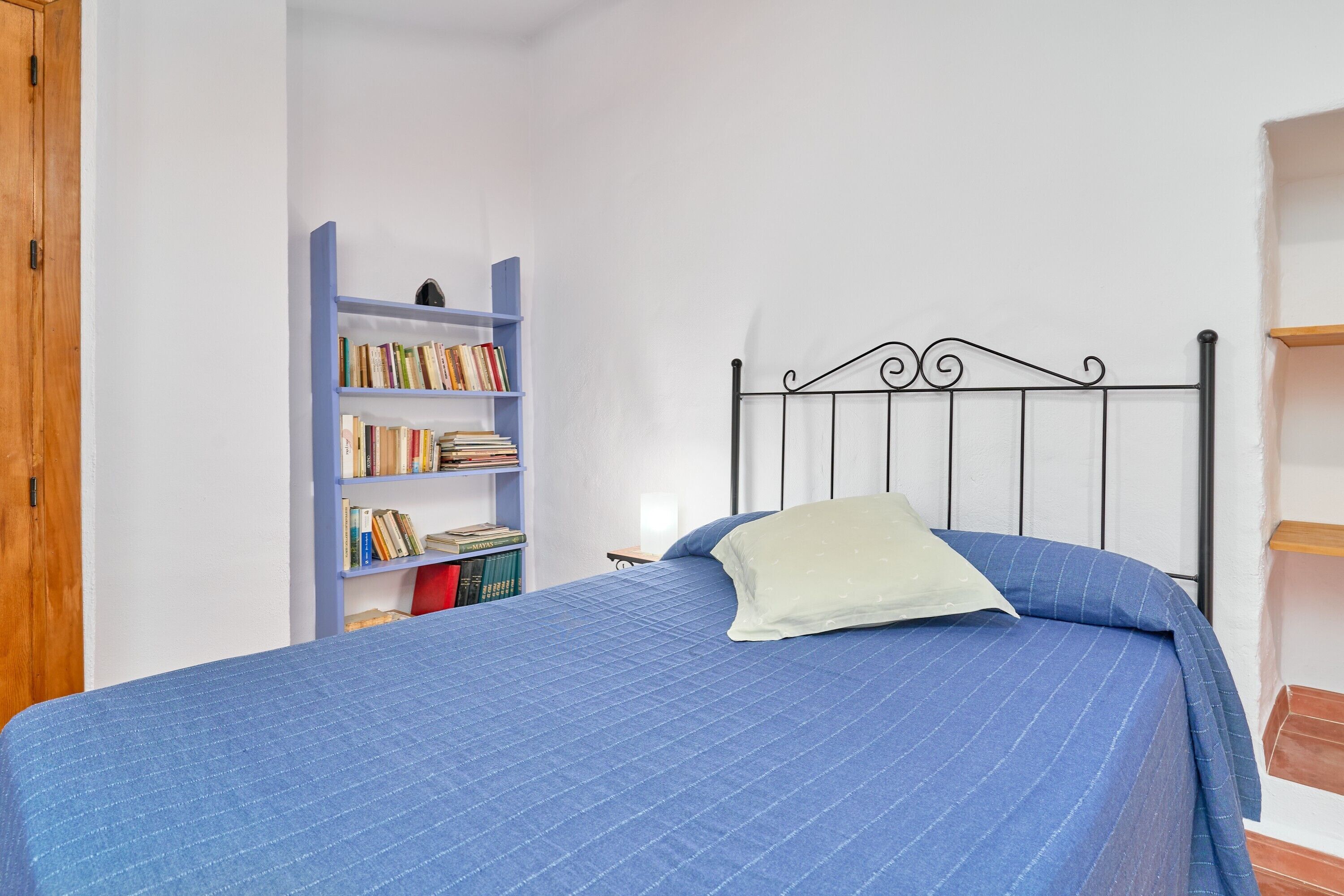 Ein Schlafzimmer mit einem Bett, einem Bücherregal und einem Holzschrank.