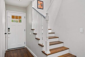 Eine Treppe mit weißen Balustraden und Holzstufen, die zu einer Tür mit Glasfenster und Schloss führt.