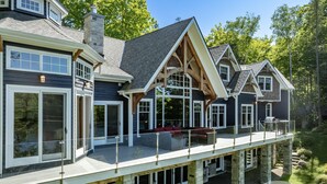 A large, two-story house with a balcony, stone foundation, and multiple windows. - Gorgeous 7 Bed, 6 Bath Family Cottage on Lake Rosseau! Muskoka Room! Pool Table! (Port Carling)