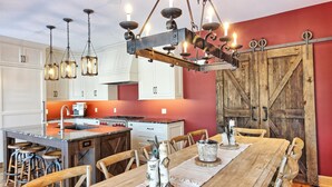 A kitchen with white cabinets, a wooden island, and a dining area with a wooden table and chairs. - Gorgeous 7 Bed, 6 Bath Family Cottage on Lake Rosseau! Muskoka Room! Pool Table! (Port Carling)