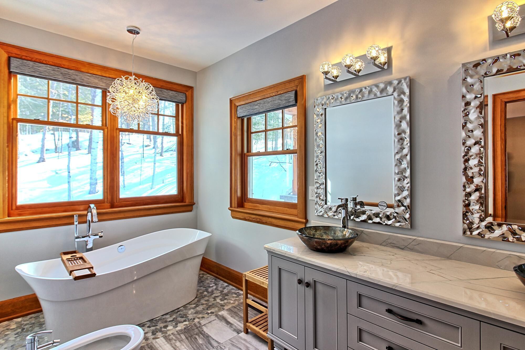 A modern bathroom with a freestanding bathtub, a vanity with a bowl sink, and a large mirror.