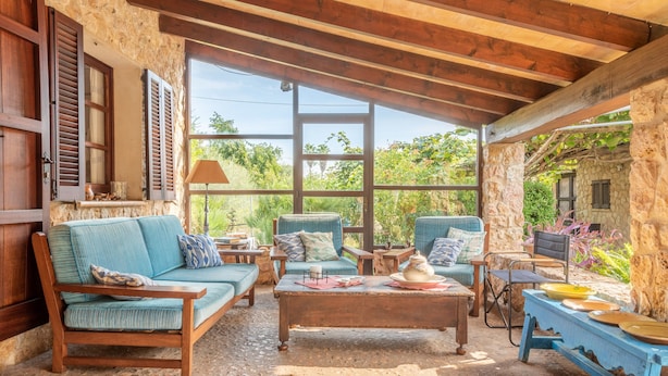 A rustic interior with a stone wall, wooden furniture, and large windows. - Villa "Can Sol" with Private Pool and Large Garden in Pollensa (Pollensa)