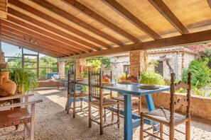 An outdoor patio with a wooden ceiling, stone walls, and a table set for dining. - Villa "Can Sol" with Private Pool and Large Garden in Pollensa (Pollensa)