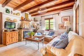 A cozy living room with wooden beams, a fireplace, a television, and comfortable seating. - Villa "Can Sol" with Private Pool and Large Garden in Pollensa (Pollensa)