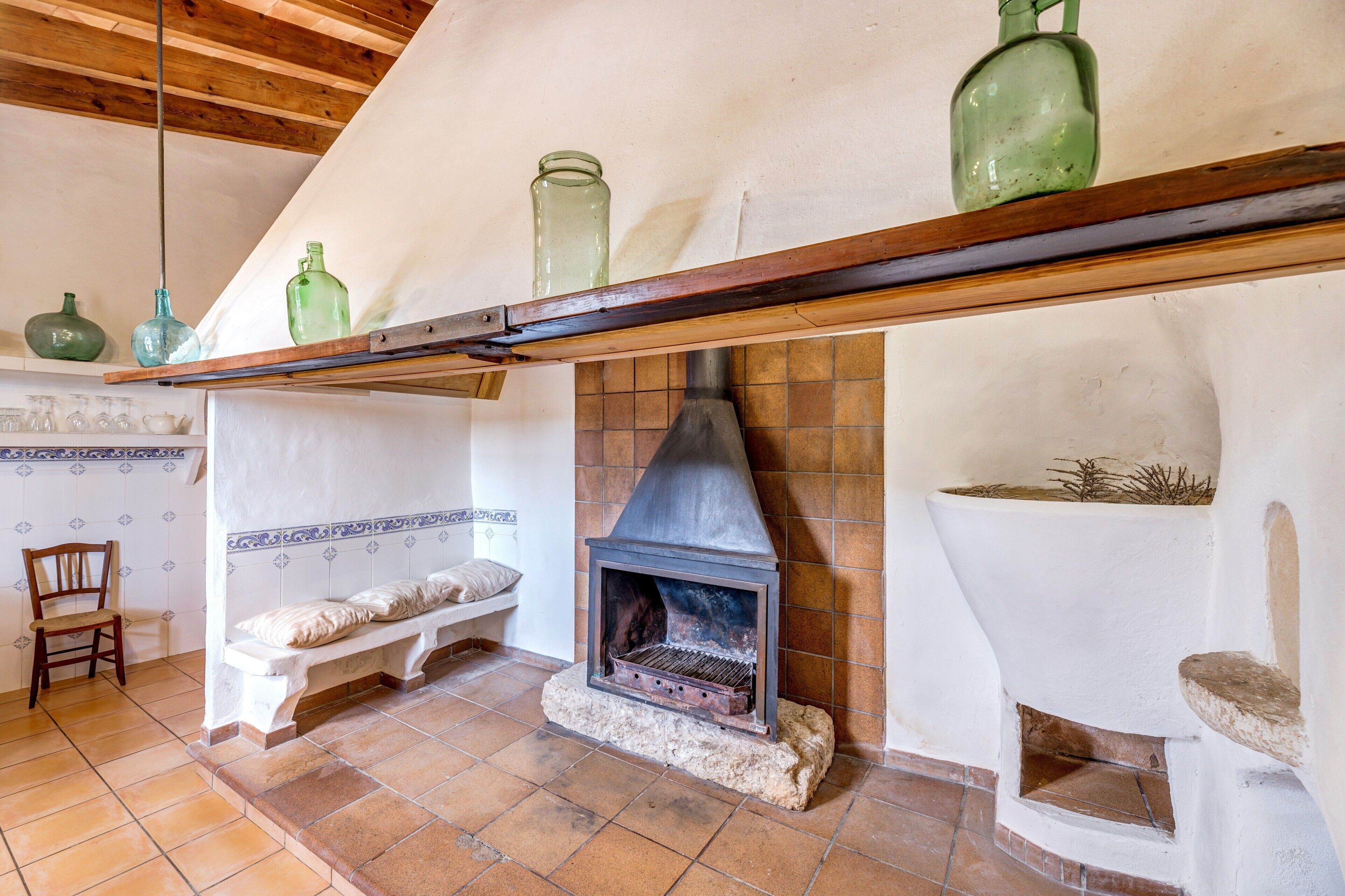 Un interno rustico con camino, travi in legno e pavimento piastrellato.