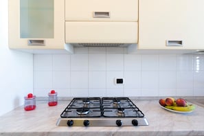 A kitchen with a gas stove, cabinets, and a fruit bowl on the counter.