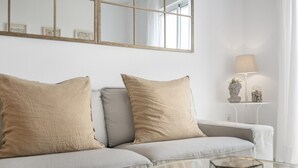 Ein modernes Wohnzimmer mit einer Couch, einem Glastisch und einer Lampe auf einem Beistelltisch.