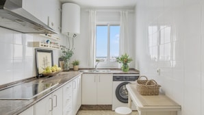 Eine kompakte Küche mit Waschmaschine, Spüle und einem Fenster mit Blick.