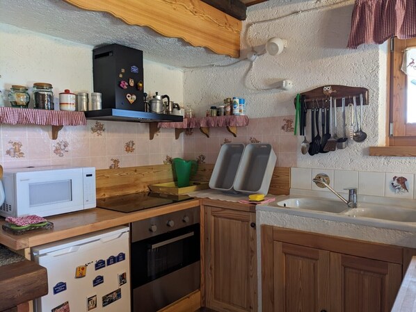 Una cucina con forno a microonde, forno, mobili in legno e lavandino.