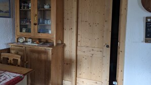 Un gabinete de madera con puertas de vidrio, una mesita con un reloj y una puerta con un recorte circular.