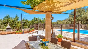 An outdoor patio with a pool, wicker furniture, and a table with a fruit bowl.
