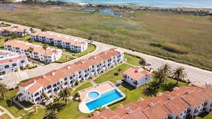 A resort with multiple white buildings, a swimming pool, and a view of the ocean. - Modern apartment in complex with pool - Girasols Gardens Sup (Son Bou)