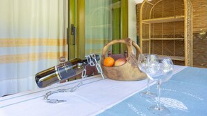 A table with a wine bottle, a fruit basket, and two wine glasses. - Cottage with Garden, Terrace, Air Conditioning, and Shared Pool (Porto Rotondo)