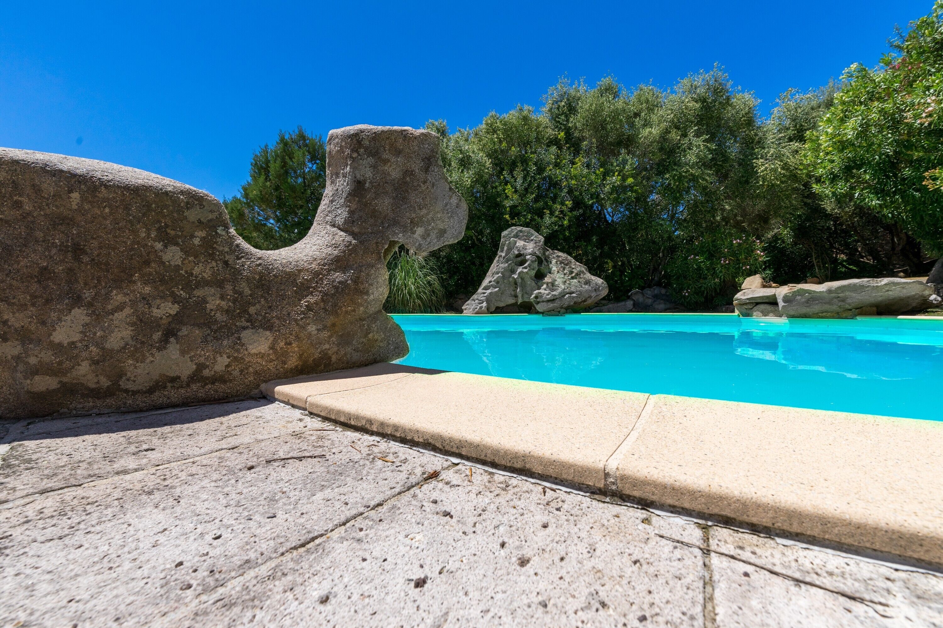 A swimming pool with large rocks and a clear blue sky.