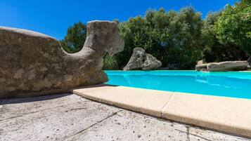 A swimming pool with large rocks and a clear blue sky.