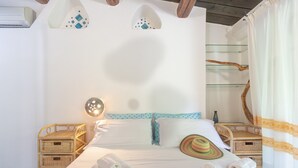 A bedroom with a bed, two nightstands, a wall-mounted light, a decorative wall piece, and a window with curtains. - Cottage with Garden, Terrace, Air Conditioning, and Shared Pool (Porto Rotondo)