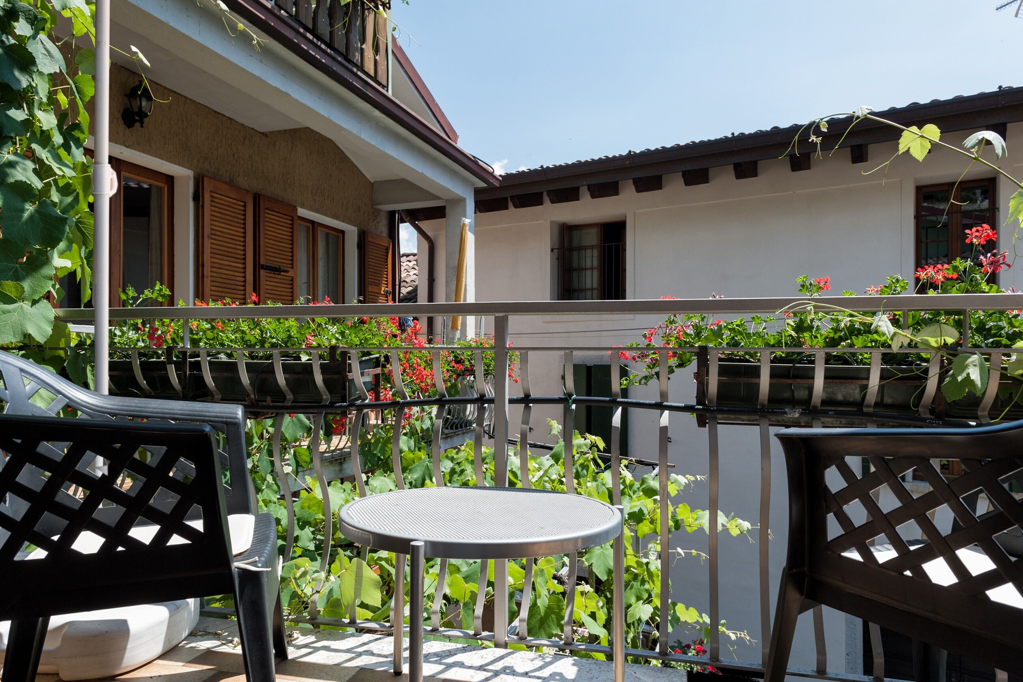 Un balcone con tavolo e sedie, circondato da piante e fiori.