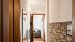 Un pasillo con puerta de madera, pared de piedra y una cama al fondo.