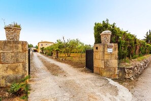 A rural property with stone walls, a dirt path, and a building in the distance.