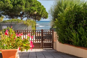 A coastal view with a wooden gate, potted plants, and a clear sky.