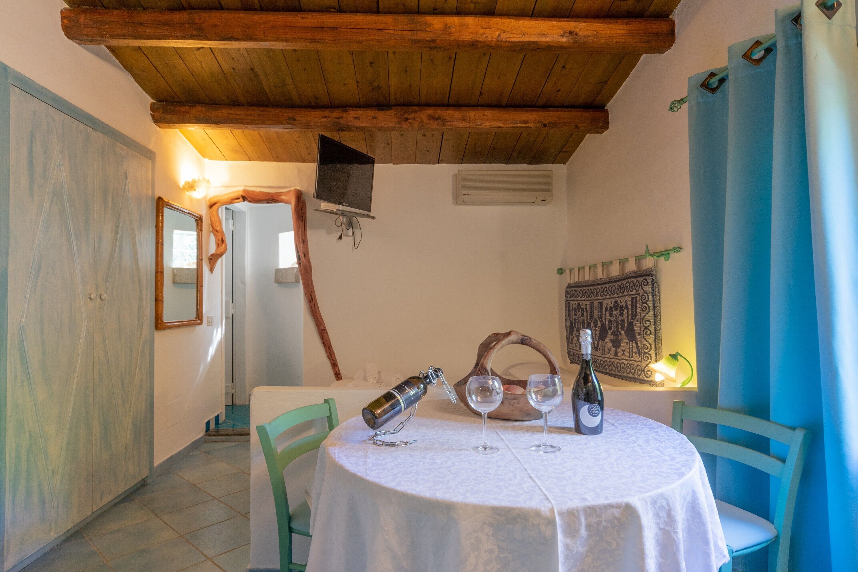 A dining area with a round table, chairs, a wine bottle, and a bottle opener.