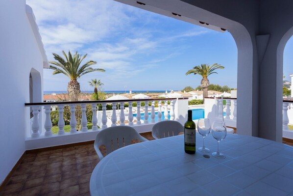 A balcony with a table, chairs, a bottle, and glasses.