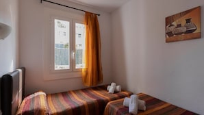 A small room with two beds, a window with curtains, a painting on the wall, and a lamp. - Family Villa with Sea Views (San Jaime Mediterráneo)