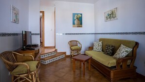 A living room with a sofa, chairs, a TV, and a staircase leading to another room. - Family Villa with Sea Views (San Jaime Mediterráneo)