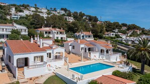 A residential area with white buildings, a swimming pool, and a hillside in the background. - Family Villa with Sea Views (San Jaime Mediterráneo)