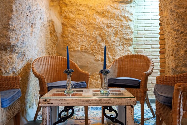 A rustic interior with wicker chairs, a wooden table, and two candles.